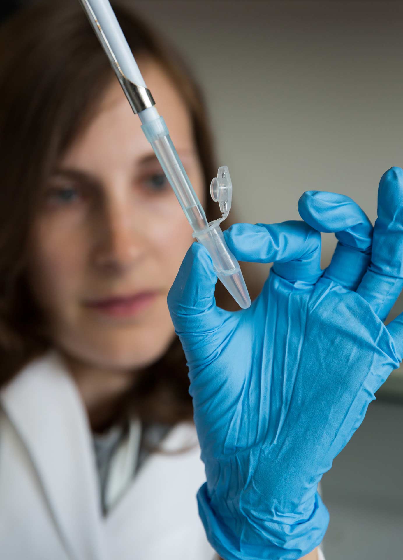 Frau im Hintergrund, Pipette und Hand im Fokus